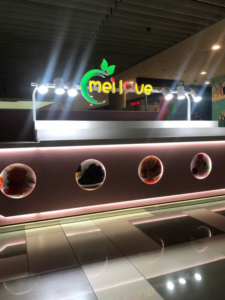 Mặt trước quầy bánh kẹo MELOVE màu hồng có logo phát sáng và hốc hình sản phẩm tại TP.HCM